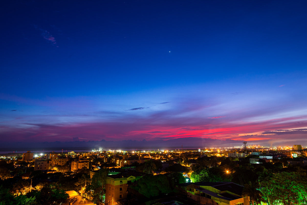 Pink clouds and a deep blue sky stretch above the glowing lights of Barranquilla.
