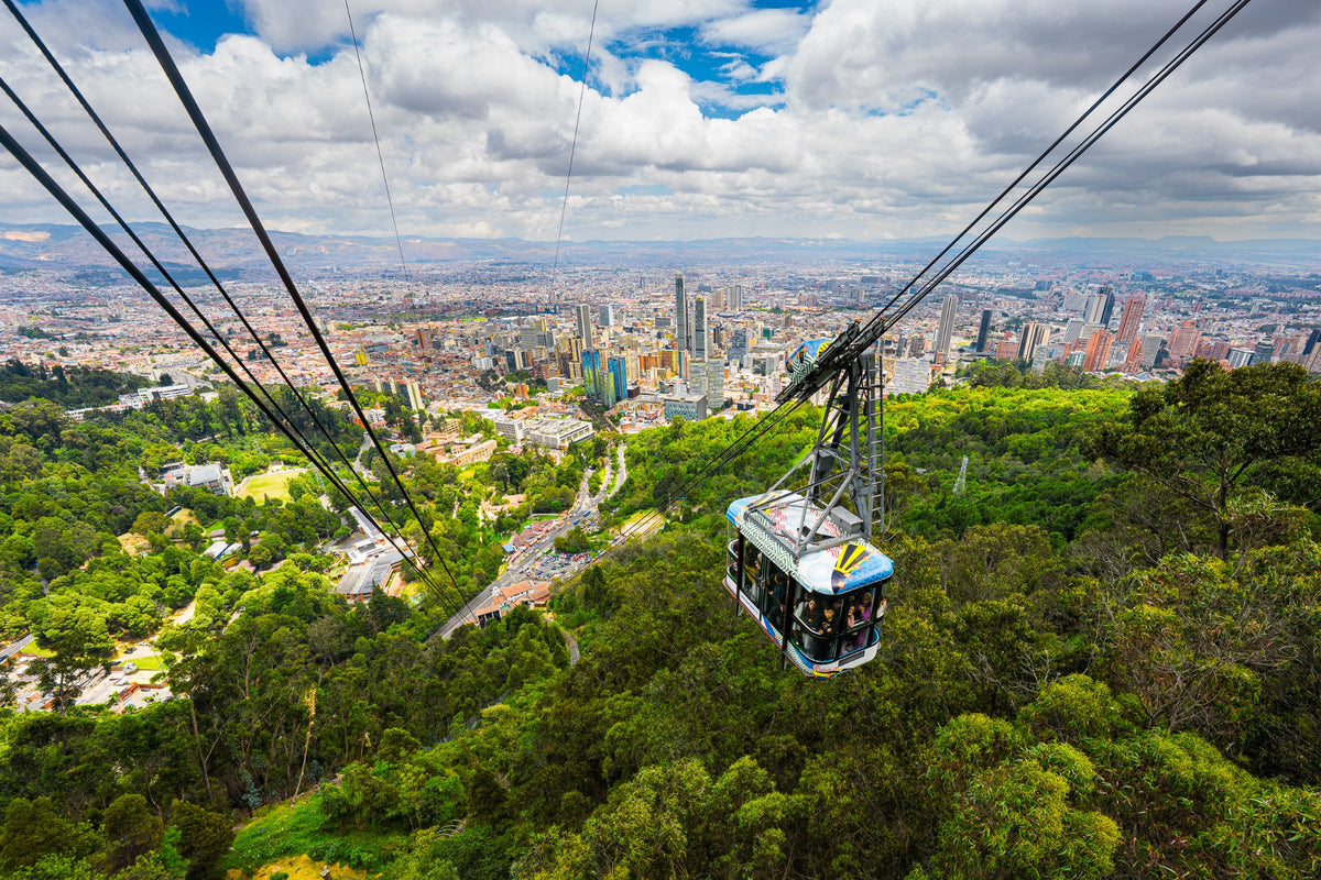 A cable car above green mountain slopes with Bogotá stretching to the horizon.
