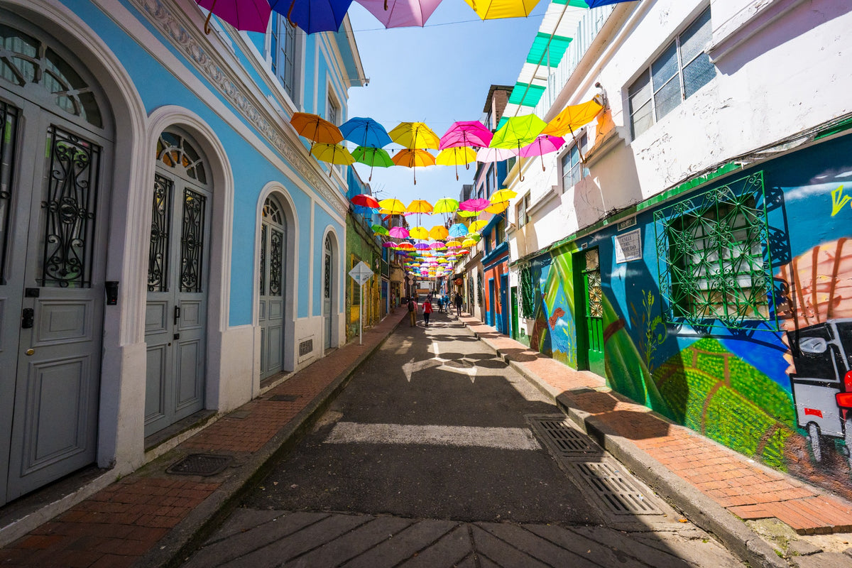 Colorful umbrellas suspended over a narrow street of painted façades.