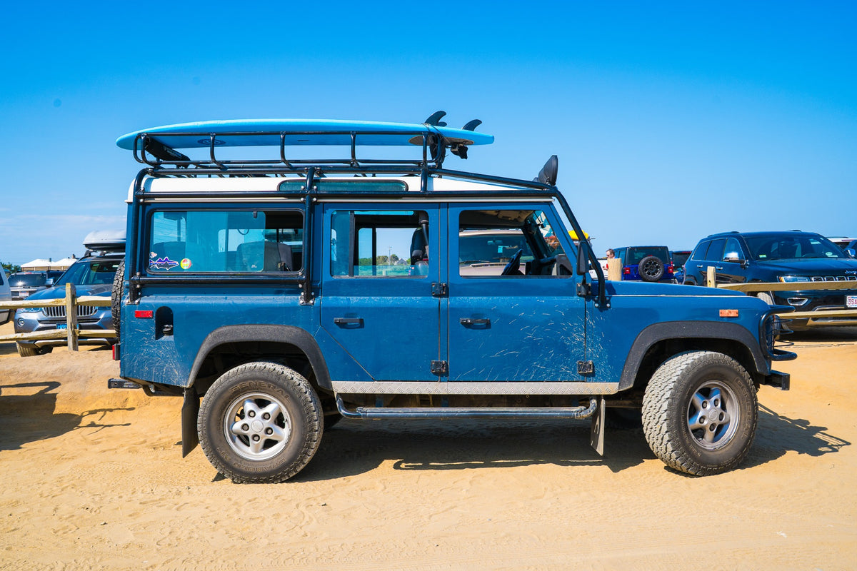 A blue Defender, a board overhead, and the promise of an Atlantic afternoon.