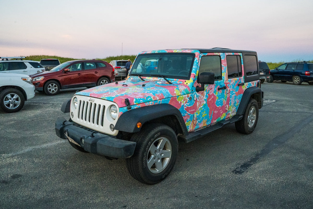 A floral Jeep wears the island in pink and turquoise beneath a soft evening sky.