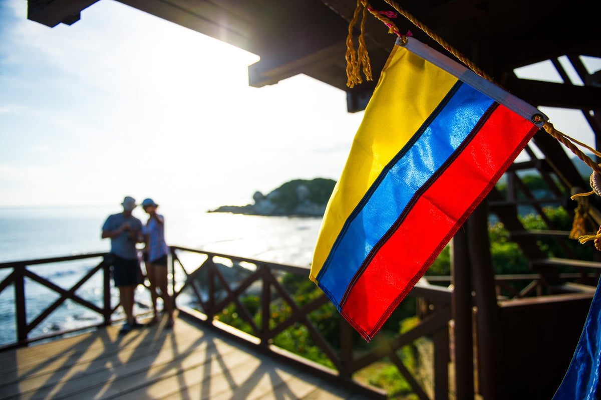 A backlit Colombian flag on the wooden lookout above the Caribbean.
