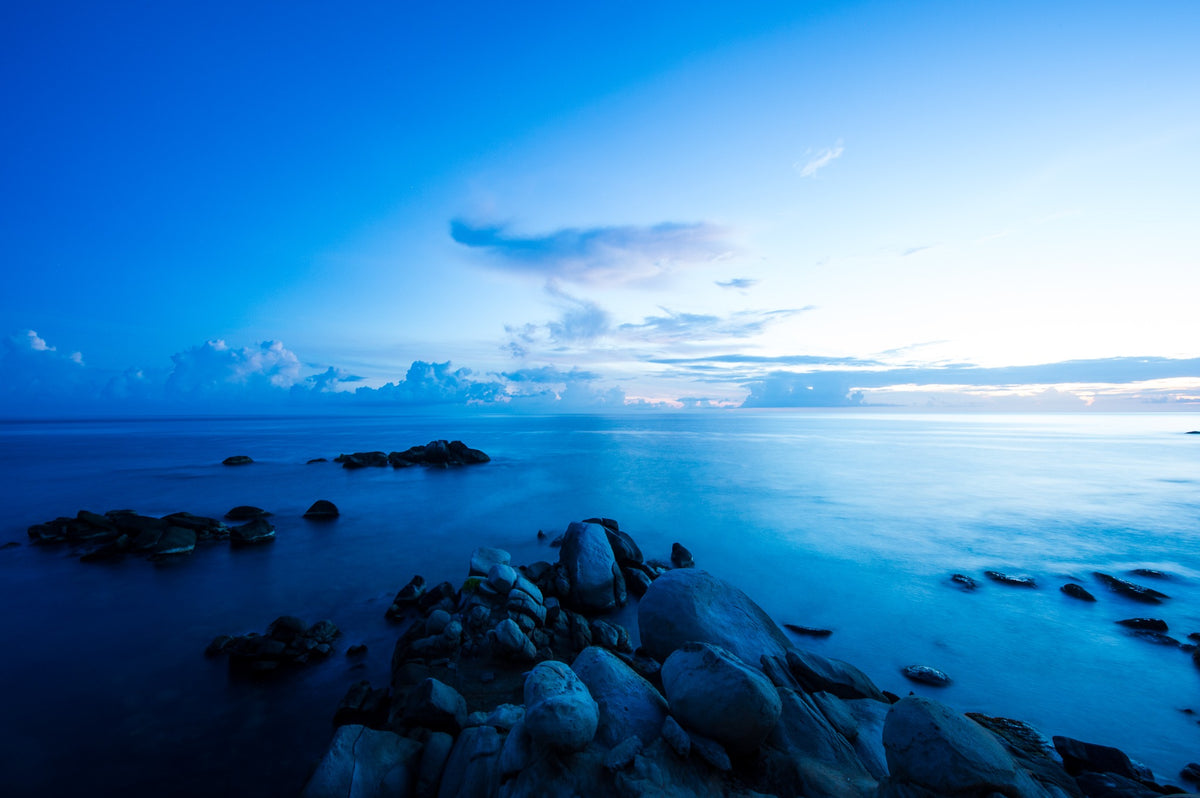 A long exposure softens the sea around foreground granite boulders.