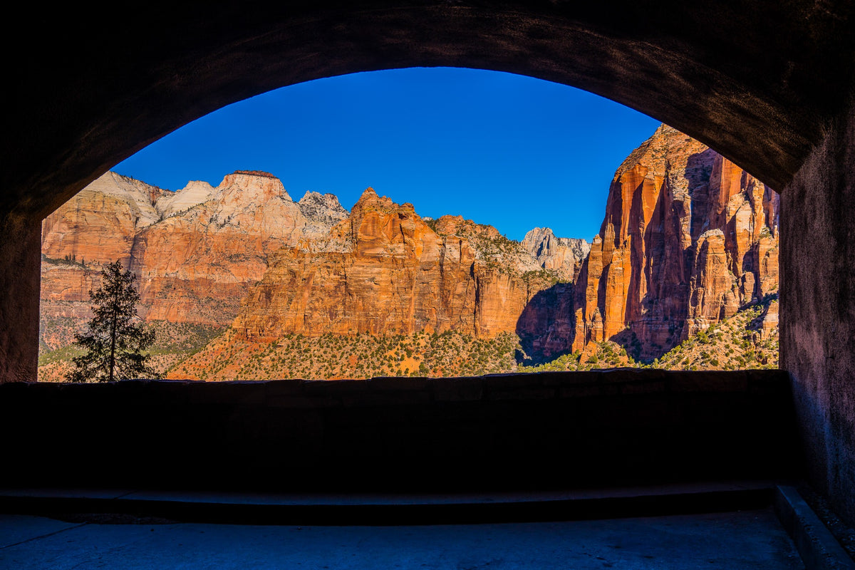 Sunlit canyon walls framed by a dark arched opening.