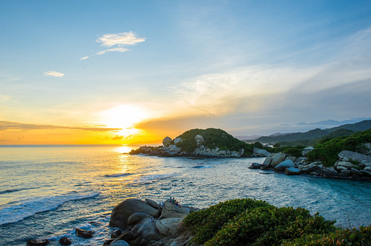 Golden sunlight spreads across the sea and granite coast at El Cabo San Juan de Guía.
