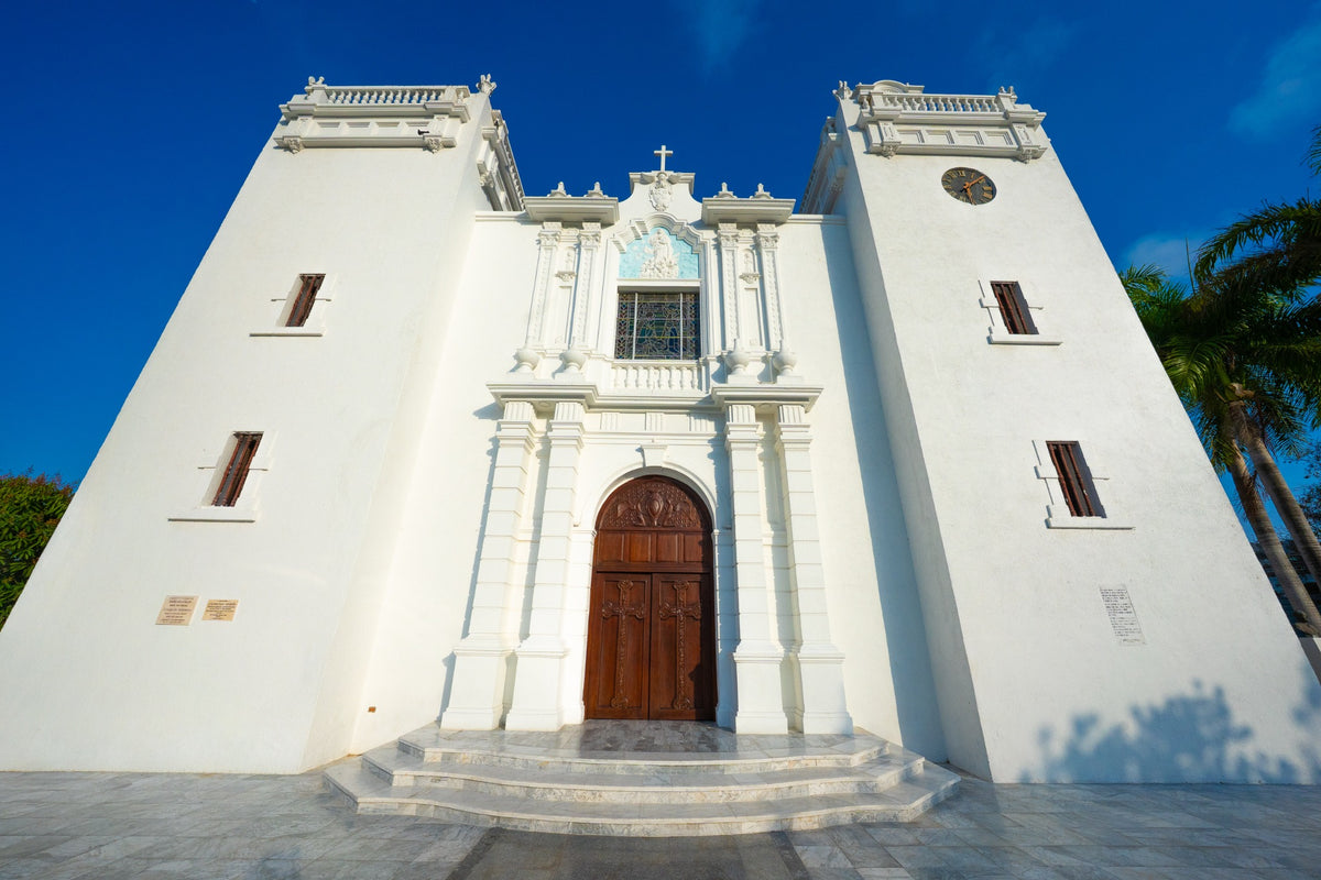 A white church facade and wooden doorway beneath a deep blue Caribbean sky.
