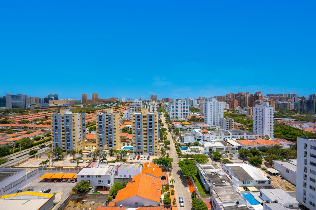 Barranquilla rooftops and apartment buildings stretch beneath a clear blue sky.