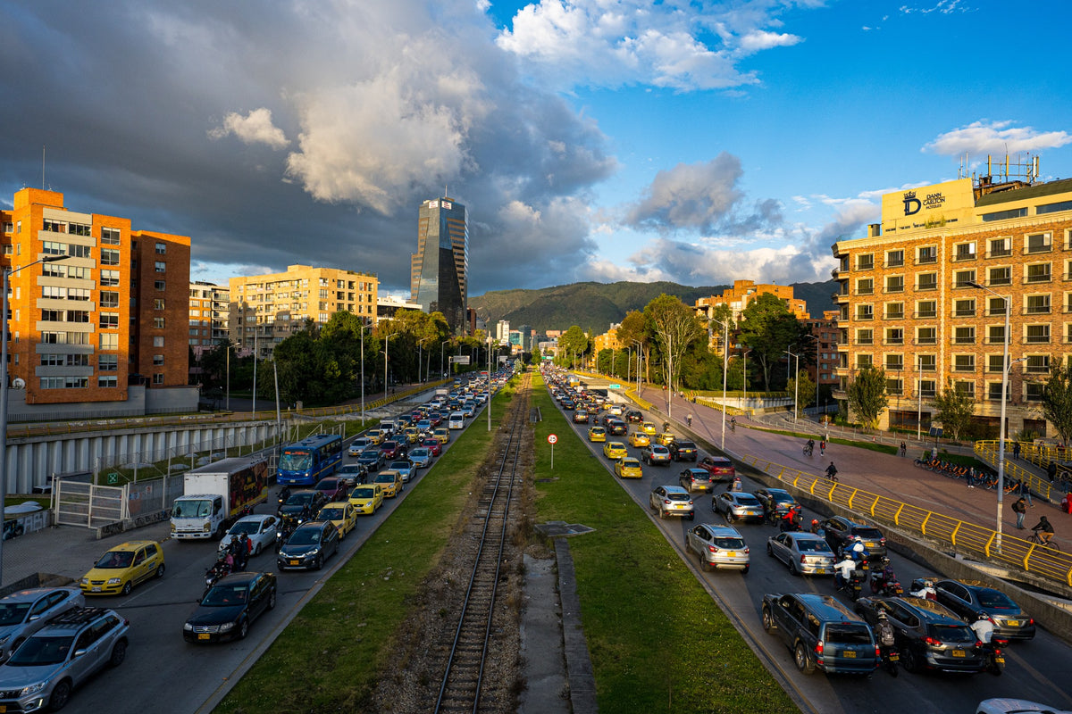Evening traffic and railway tracks leading toward the mountains in warm light.