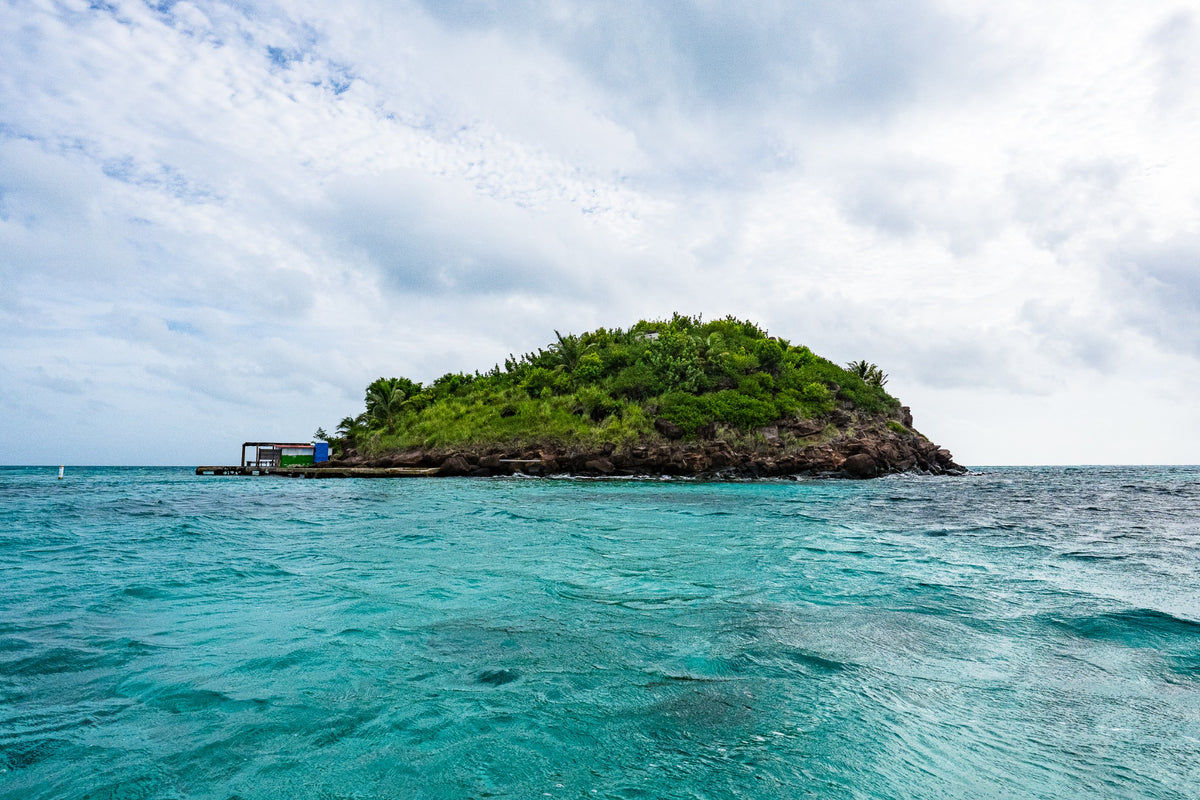 A small green rocky cay surrounded by turquoise water.