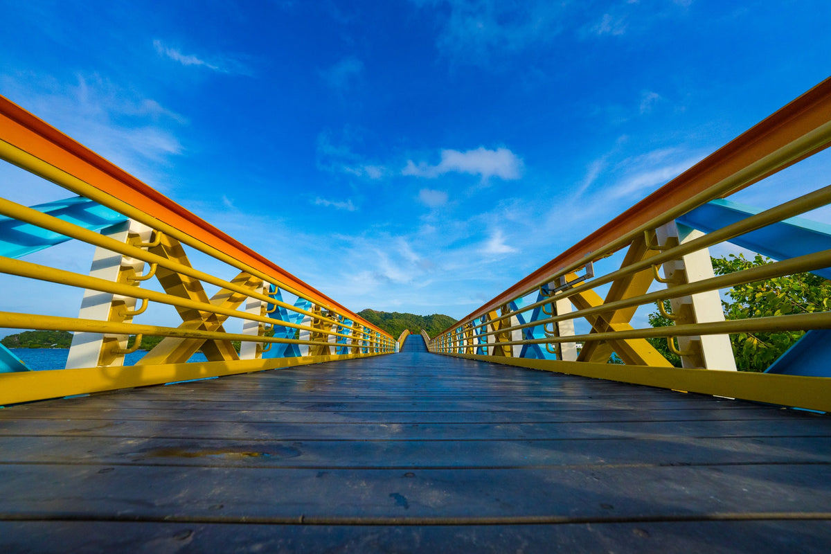 Yellow and blue bridge railings converge beneath a bright Caribbean sky.