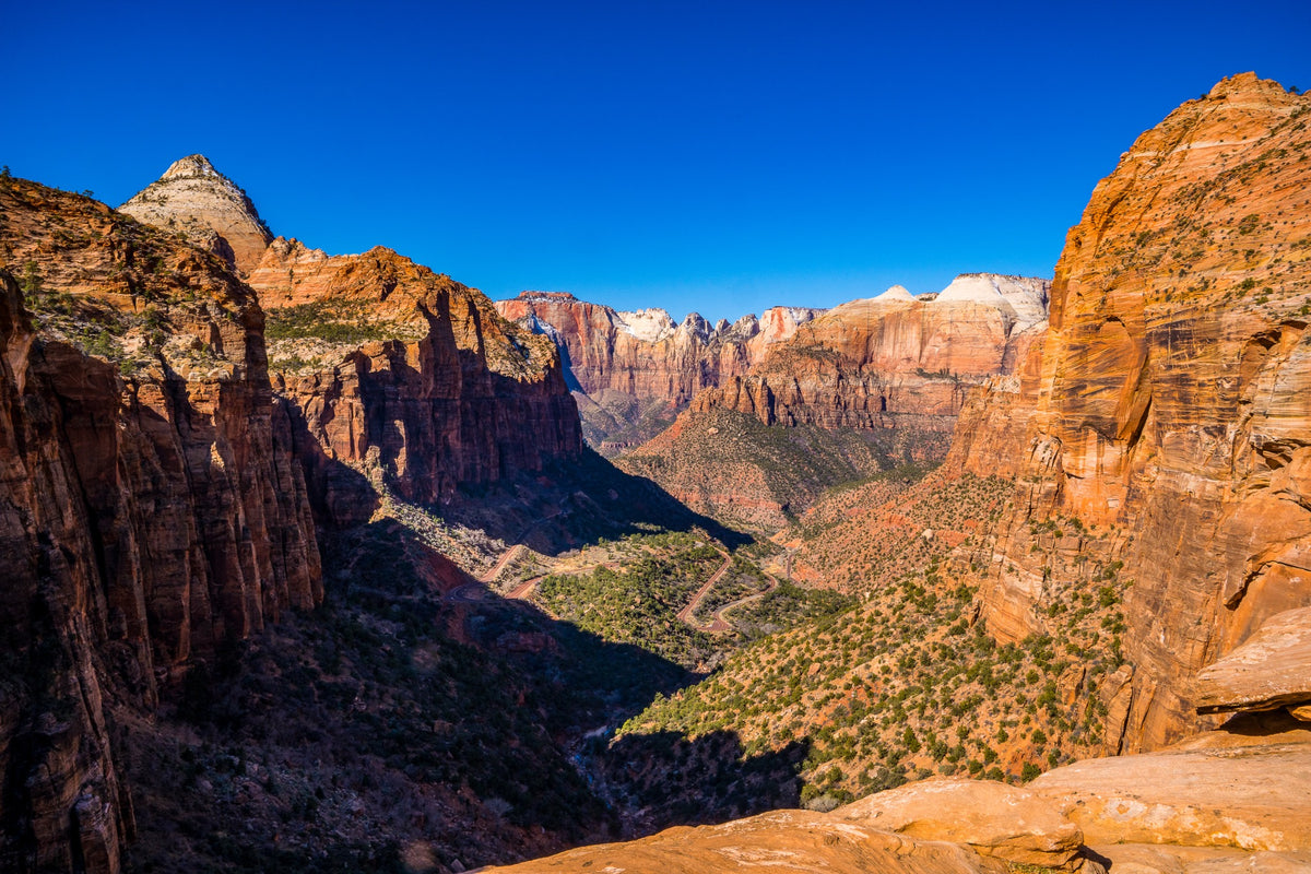 A vast sandstone canyon with a winding road far below.