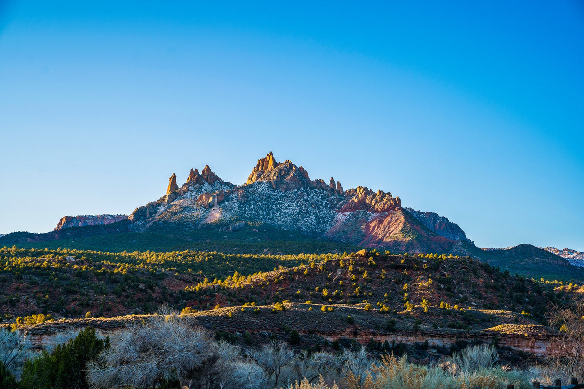 Sunlight touches a jagged ridge and terraces of green vegetation.